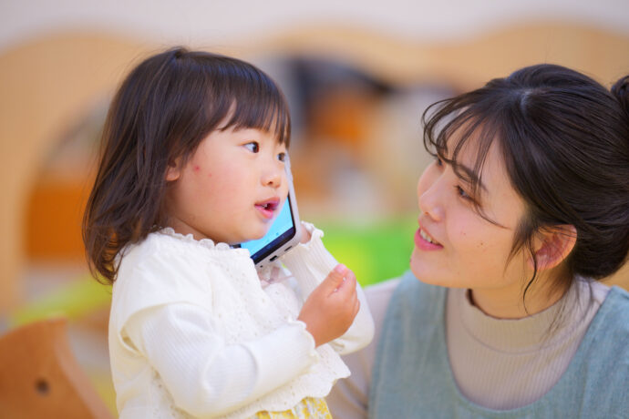 スマホで電話する子どもと大人