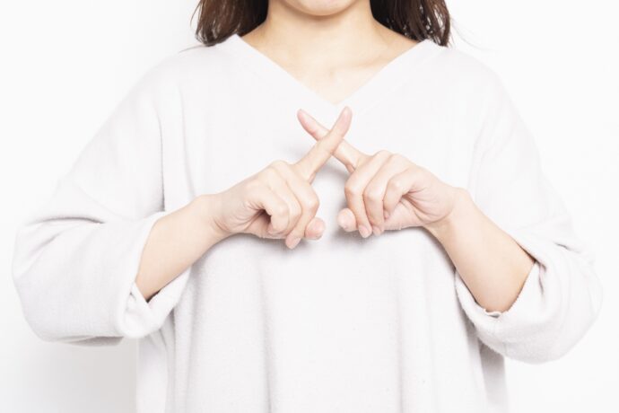 手でバツマークを作る女性