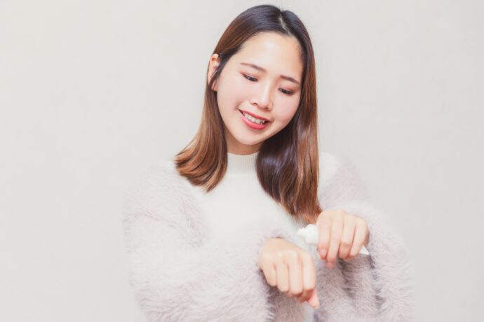 笑顔でハンドクリームを塗る女性