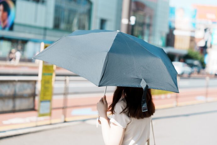 日傘をさして紫外線対策する女性の後ろ姿