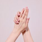 ピンクのバックに両手を交差させる女性の手