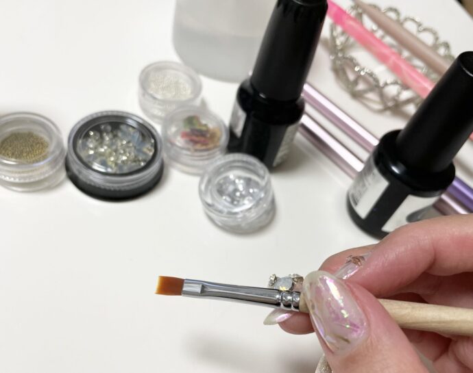 ジェル筆を持つ手とネイルアイテム