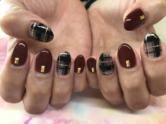 ボルドーろブラックチェックネイルをした手
