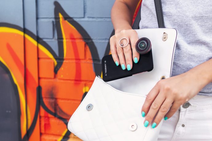 鮮やかなシアンカラーのネイルでスマートフォンを持つ女性の写真