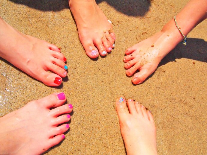 夏のビーチで色とりどりなフットネイルをした足元の集合写真