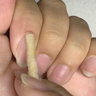 コットンを巻いたオレンジウッドスティックで甘皮を押し上げている写真