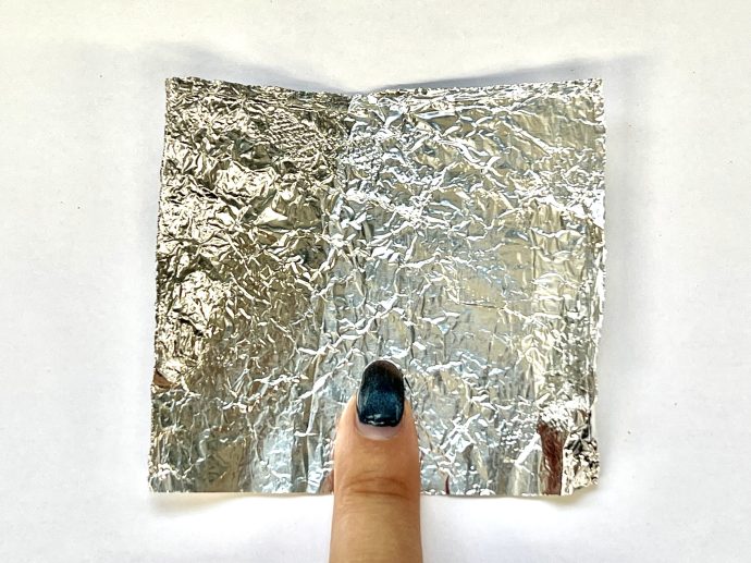 指先を包めるサイズにカットされたアルミホイルに指を置いている写真