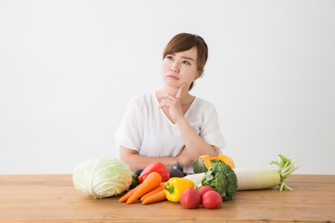 野菜を前に悩んでいる女性の写真