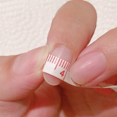 柔らかいメジャーで爪の横幅を測っている写真