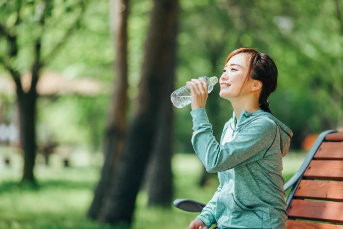 ベンチに座って水を飲む女性