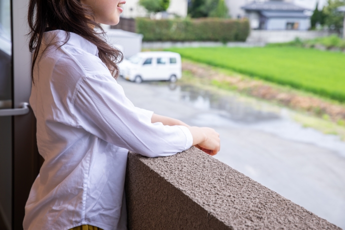 ベランダで外の景色を見ている女性