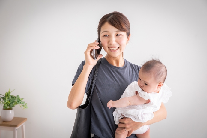 赤ちゃんを抱っこしつつ電話をしているママ