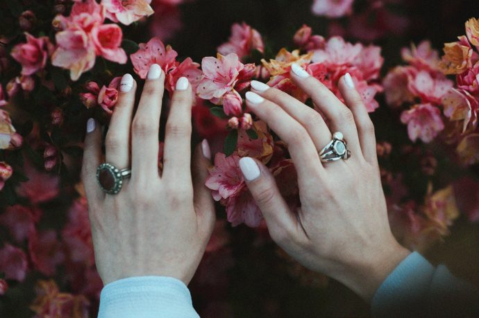 ピンクの花に手を伸ばしている写真