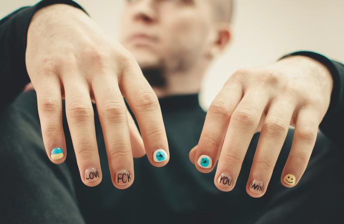 両手にニュアンスネイルをして座っている男性