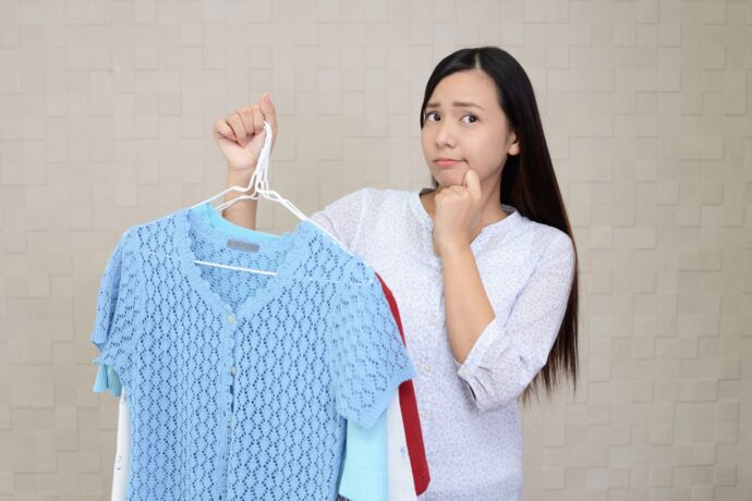 服を持って悩んでいる女性