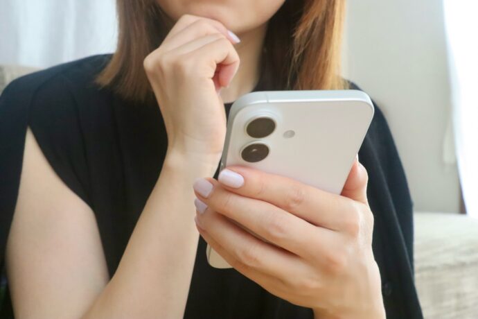 スマホを持って悩む女性