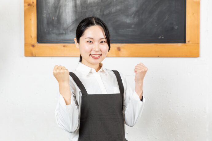 ガッツポーズをするエプロンをつけた女性