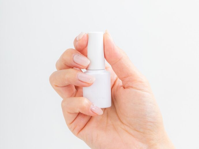 白のネイルボトルを持った手