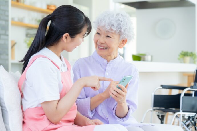 スマホを見ながら笑顔で話す高齢者と若者