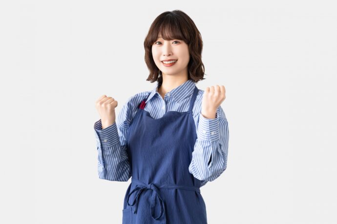 エプロンを付けてガッツポーズをする女性