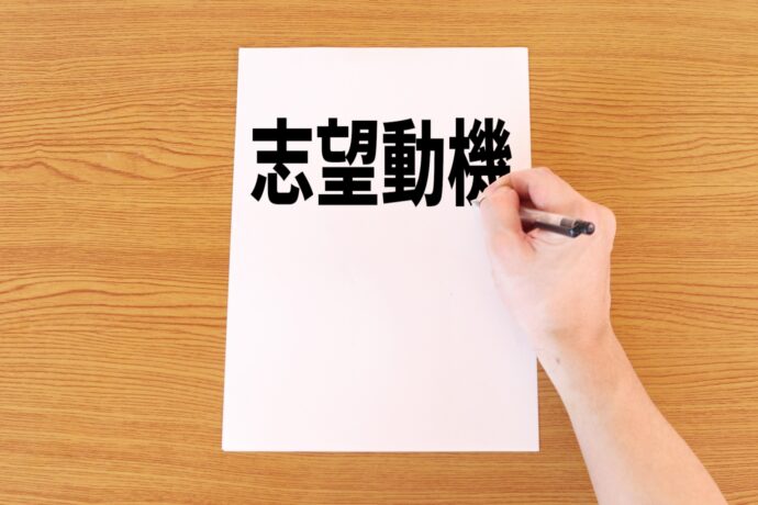 志望動機と書かれた用紙とペンを持つ手