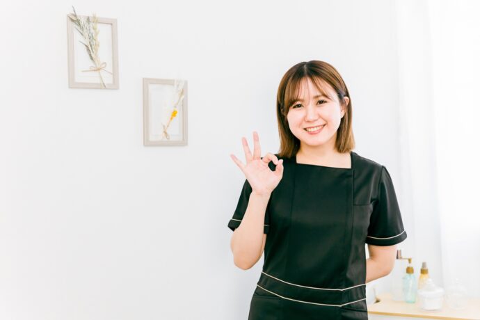右手でOKサインを作るサロン勤務の女性