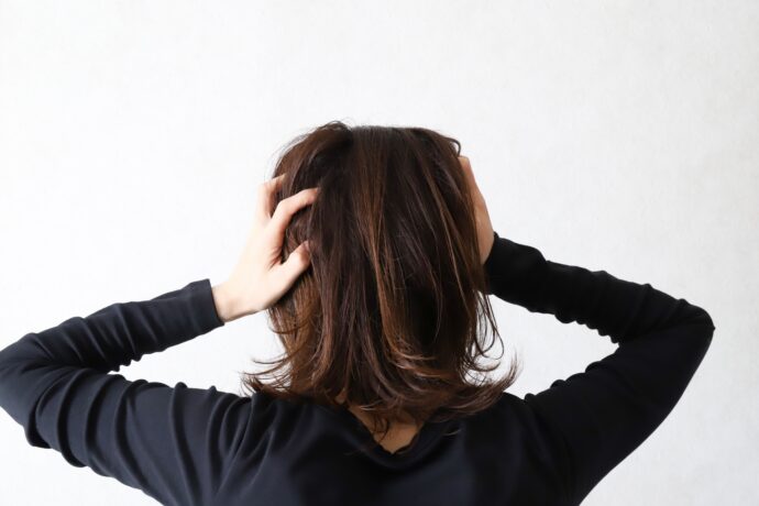 頭を抱えて悩む女性の後ろ姿