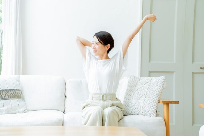 ソファーに座って伸びをする女性