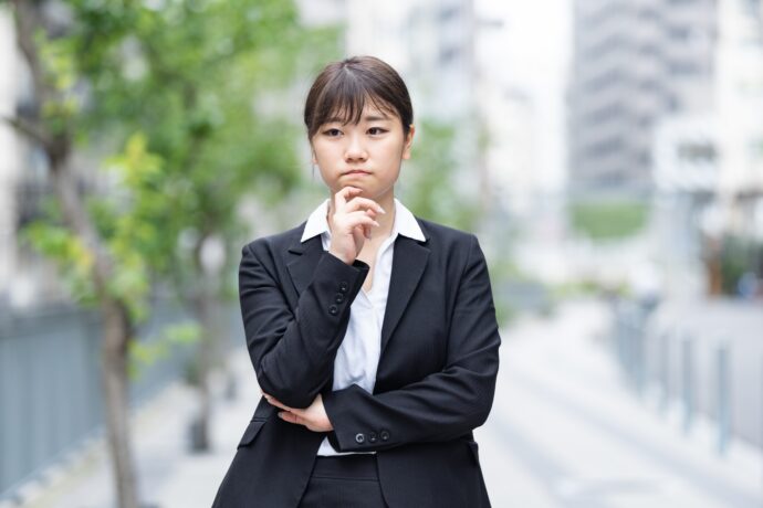 困った顔のスーツ姿の若い女性の画像
