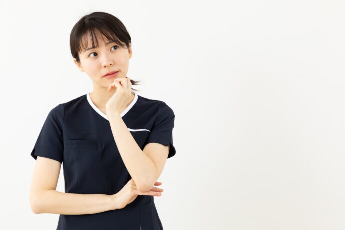 顎に手を当てて考え中のユニホームを着た女性