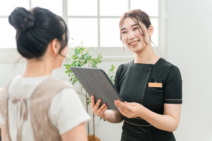 カルテを持ちカウンセリング中のネイリストとお客さん