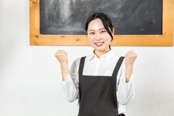エプロンを付けた女性がガッツポーズをしている