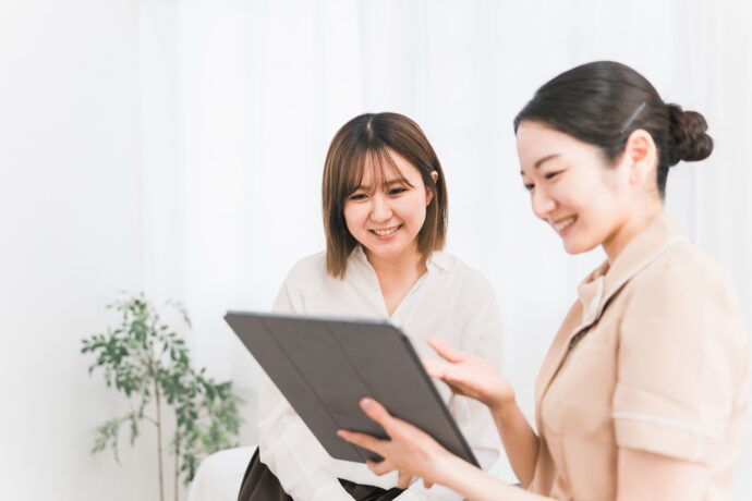 カルテを持ち接客中のネイリストとお客さん