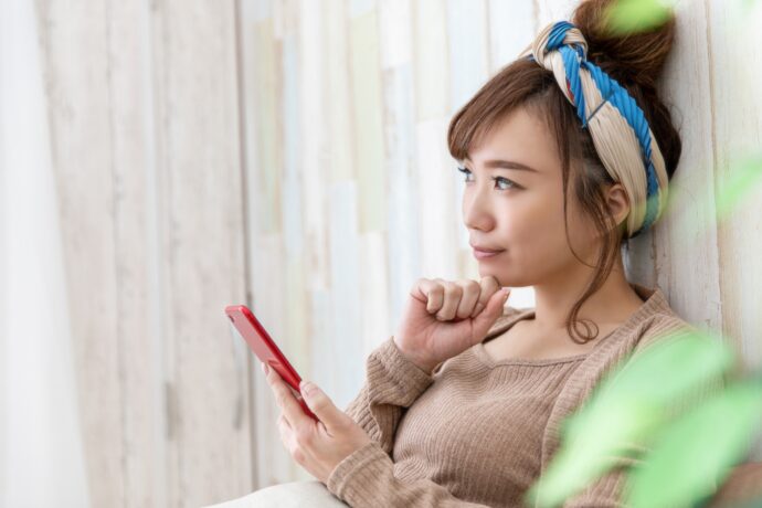 スマホを持って悩む女性