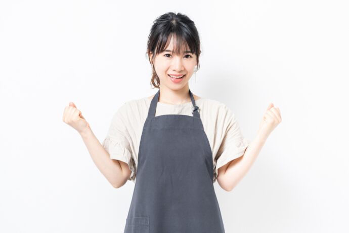 エプロンを付けてガッツポーズをする女性
