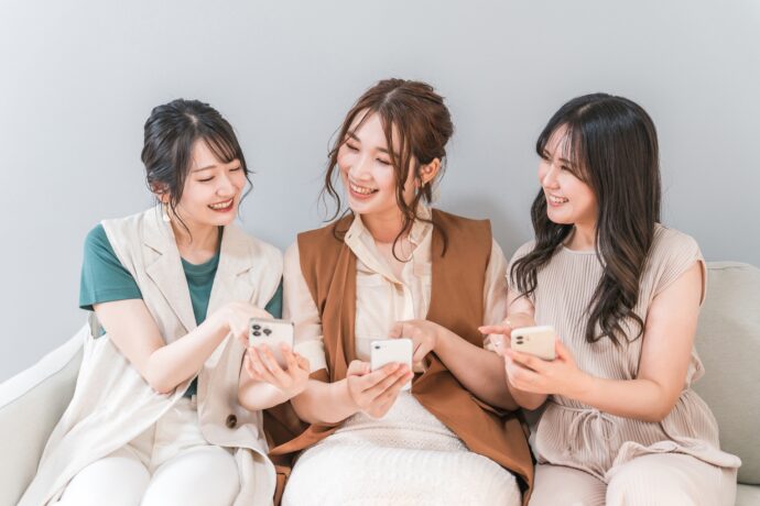 スマホを操作して会話をする女性たち