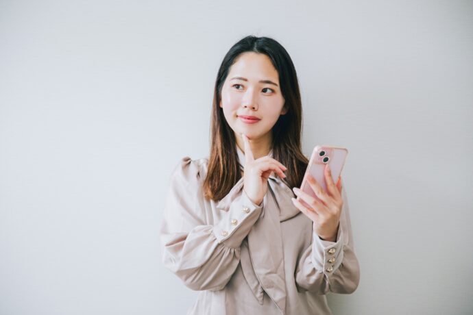 スマホを片手に悩む女性
