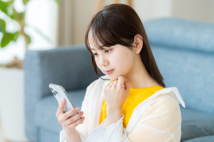 スマホを見て悩む女性