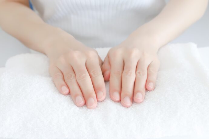 白いタオルに乗せたケア後の女性の手