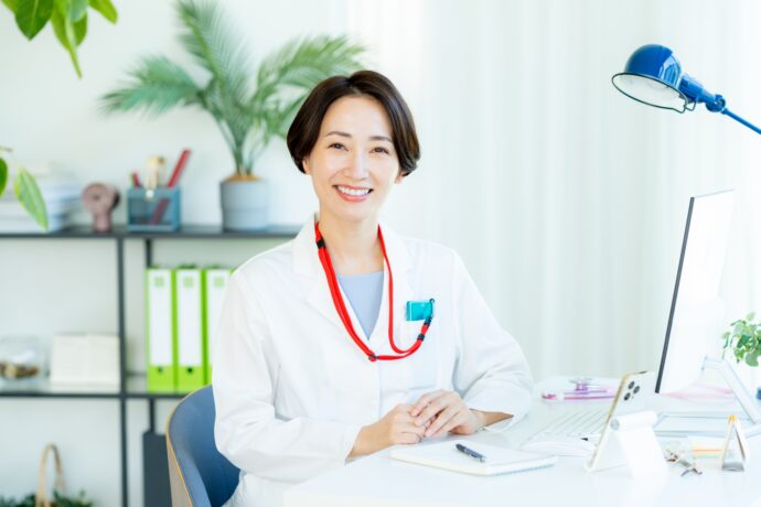 笑顔で座っている白衣を着た女医