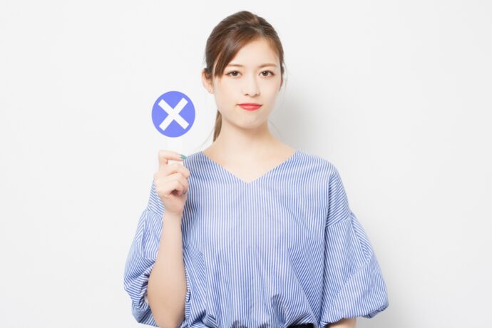 バツの札を上げる女性