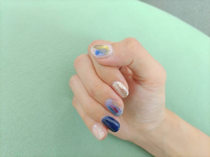 ブルーのランダムネイルをした手元