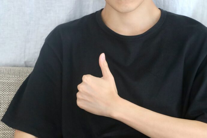 黒Tを着て手でグッドをする男性