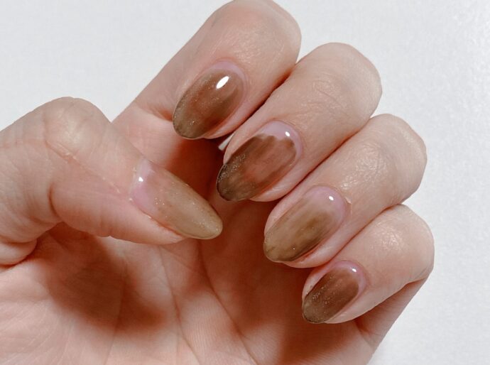 ブラウンのランダムネイルをした手元