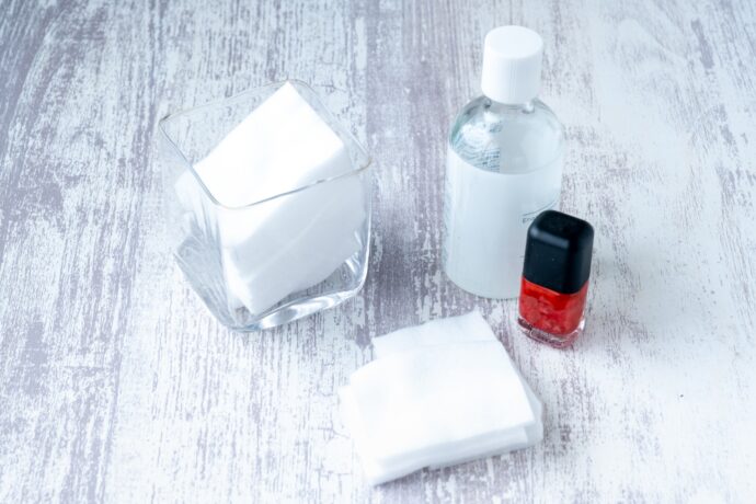 マニキュアボトルと除光液とコットンが置かれている