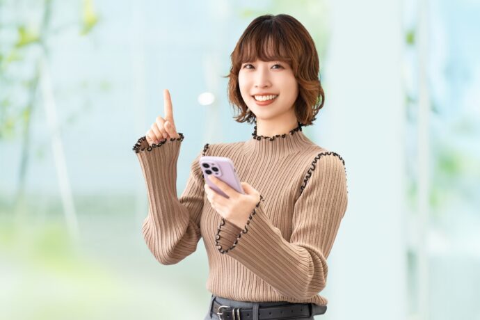 スマホを持ち指を指す女性