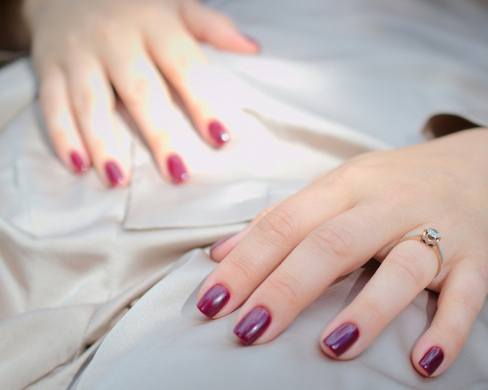 ボルドーのワンカラーネイルをした手元のアップ
