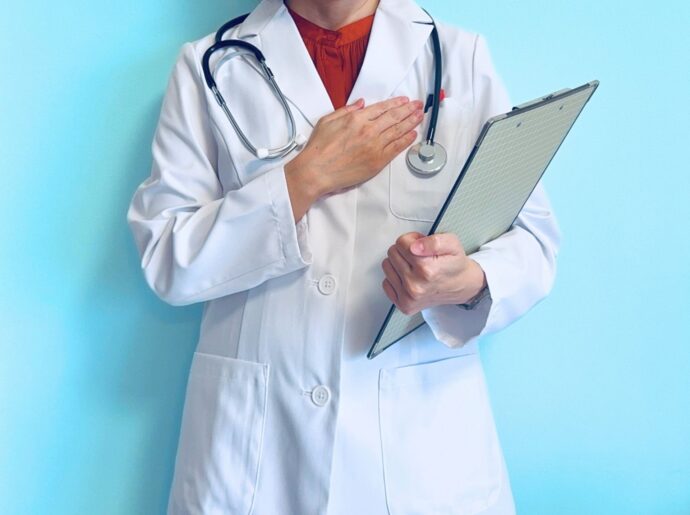 カルテを持ち胸に手を当てる医師