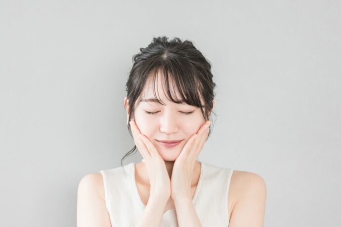 両手を頬に当てて微笑む女性