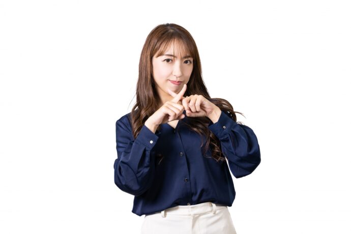 バツマークをつくる女性